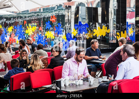 Menschen sitzen in einem Straßencafé in Covent Garden mit den Spiegeln reflektieren London hinter. Stockfoto