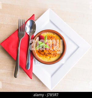 In einem Restaurant serviert eine Creme Brulee; Dessert; Essen; Süße; Pudding; Besteck; Himbeeren; Lecker; Attraktive Präsentation; Zu behandeln; Nachsicht; Luxus Stockfoto