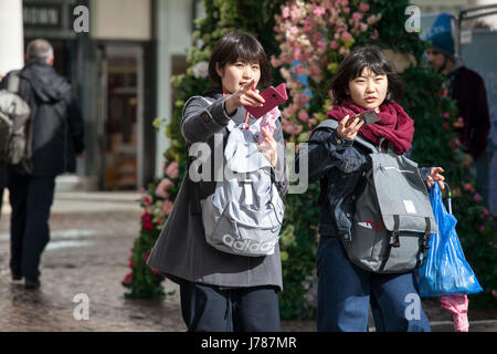 LONDON, ENGLAND - 12. März 2017 zwei japanische Touristen mit rosa Telefone und Rucksäcke gehen zum Einkaufen Stockfoto
