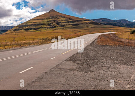 Gebogene leer ländlichen Asphaltstraße durch trockenen Winter Berglandschaft gegen blauen Wolke Himmel Horizont n Orange Free State in Südafrika Stockfoto