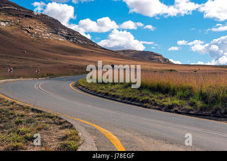 Gebogene leer ländlichen Asphaltstraße durch trockenen Winter Berglandschaft gegen blauen Wolke Himmel Horizont n Orange Free State in Südafrika Stockfoto