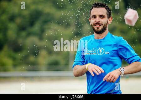 Mann-Läufer auf Wasserstelle wirft Schwamm Spritzwasser im Rennen Spring Mountain marathon Stockfoto