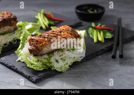 Oriental gebratenes Schweinebauch mit knuspriger Haut mit Gemüse und Nudeln Stockfoto