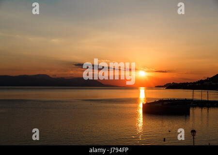 Sonne berührt Absetzen über das Meer, die rote Scheibe der Sonne am Horizont Stockfoto