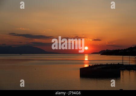 Sonne berührt Absetzen über das Meer, die rote Scheibe der Sonne am Horizont Stockfoto