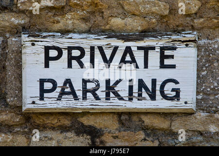 Ein alten und abgenutzten Privatparkplatz Zeichen an einer alten Steinmauer genagelt. Stockfoto