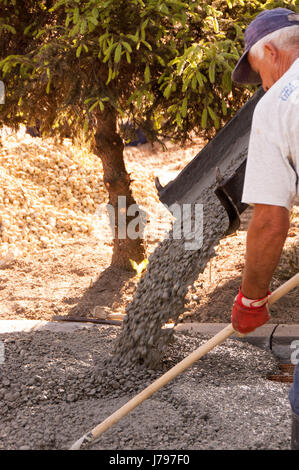 Arbeiter arbeiten Betonieren Parkplätze vor dem Haus. Mason Arbeiter Nivellierung Beton mit Kellen Mason Hände verbreiten Beton gegossen. Stockfoto