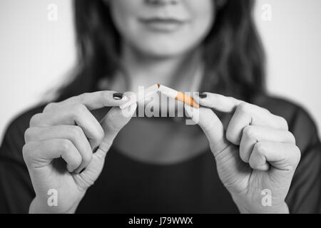 Nahaufnahme Portrait junge attraktive Frau Zigarette in Stücke brechen. Studio gedreht selektiven Fokus auf grau isoliert. Sucht-Konzept Stockfoto