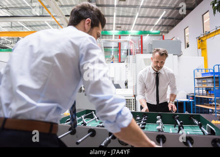 Zwei Kollegen spielen Tischfußball in Fabrik Stockfoto