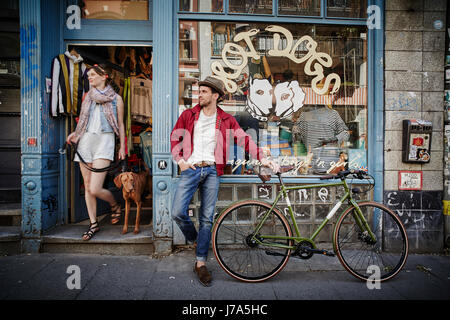 Deutschland, Hamburg, St. Pauli, Mann mit Fahrrad wartet vor Vintage-Shop, Frau mit Hund kommen Stockfoto