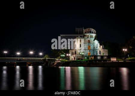 Eine Nacht-Kamerafahrt von Atomic Bomb Dome, die in den Himmel stockdunkel abhebt.  Schöne Laternenmast Starburst Effekte im Wasser gespiegelt. Stockfoto