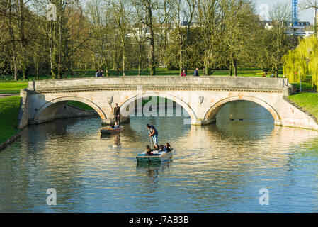 Touristen auf Punt Boote mit steinernen Brücke über den Fluss Cam an einem sonnigen Frühlingstag, Cambridge, Großbritannien Stockfoto