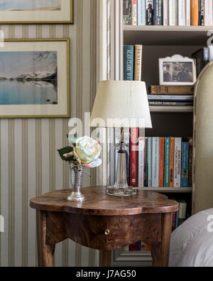 A lamp from Valerie Wade on an antique burr walnut table. The striped fabric lining the walls is by Nicole Fabre. Stockfoto