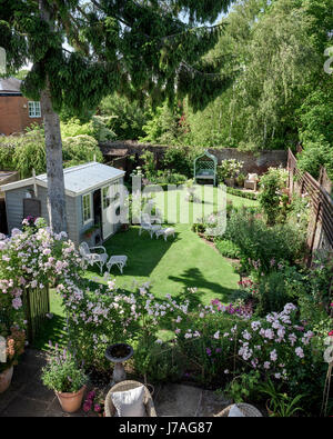 Blick vom Balkon auf Englisch ummauerten Garten mit Gartenhaus und rose Bogen Stockfoto