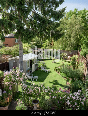 Blick vom Balkon auf Englisch ummauerten Garten mit Gartenhaus und rose Bogen Stockfoto
