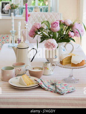 Biskuit, Emaille Teekanne und rosa Pfingstrosen auf gestreifte Tischdecke von Susie Watson Designs Stockfoto