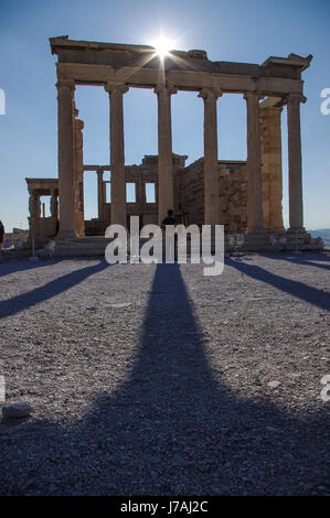 Glitzernde Sonne warf einen langen Schatten von das Erechtheion in der Akropolis, Athen. Eine einsame Touristen beobachtet. Stockfoto