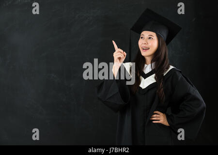 asiatische Mädchen zeigen Luft auf Blackboard und Hand in der Taille, die gute Idee mit Exemplar lächelnd. Porträt der Doktorand Bildkonzept. Stockfoto