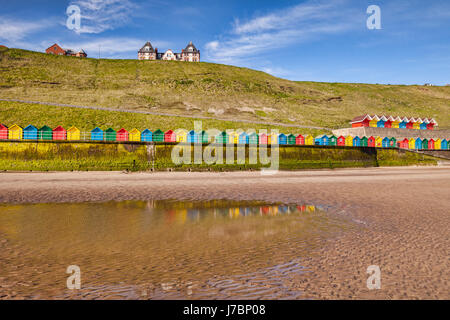 Strand Hütten entlang der Promenade und reflektiert in einem Pool am Nordstrand, Whitby, North Yorkshire, England, UK, an einem hellen sonnigen Frühlingsmorgen. Stockfoto