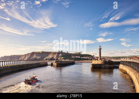 Angelboot/Fischerboot nähert sich die Einfahrt in den Hafen der alten Fischerei Hafen von Whitby, North Yorkshire, England, UK. Stockfoto