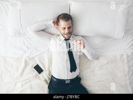Ansicht von oben. Junge hübsche Geschäftsmann mit Brille auf dem Bett liegend Stockfoto