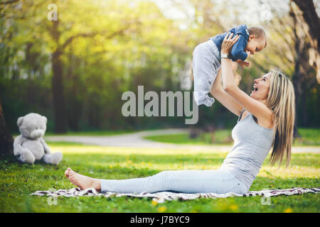 Erfreut Mutter mit ihrem einjährigen Sohn im Freien in einem park Stockfoto