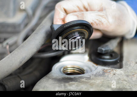 Die Hände des Kfz-Mechaniker Schrauben Sie die Kappe von der Öl-Füller. Die Mechaniker in Einweg-Handschuhe schraubte den Öleinfüllstutzen des Motors. Stockfoto