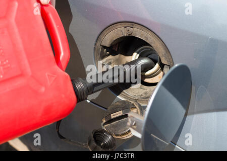 Das Auto-Tank Kraftstoff aus einem Kunststoff Kanister hinzufügen. Kraftstoff aus einem Kunststoff Kanister nachfüllen. Panne. Kein Kraftstoff. Hinzufügen von Brennstoff. Stockfoto