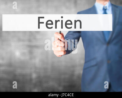 Ferien (Urlaub in deutscher Sprache) - Geschäftsmann Hand mit Schild. Wirtschaft, Technologie, Internet-Konzept. Stock Foto Stockfoto