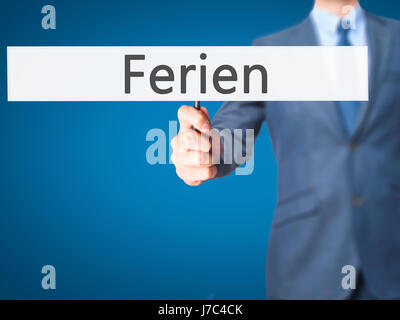 Ferien (Urlaub in deutscher Sprache) - Geschäftsmann Hand mit Schild. Wirtschaft, Technologie, Internet-Konzept. Stock Foto Stockfoto