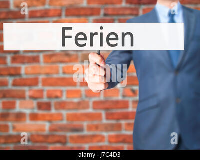 Ferien (Urlaub in deutscher Sprache) - Geschäftsmann Hand mit Schild. Wirtschaft, Technologie, Internet-Konzept. Stock Foto Stockfoto