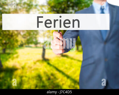 Ferien (Urlaub in deutscher Sprache) - Geschäftsmann Hand mit Schild. Wirtschaft, Technologie, Internet-Konzept. Stock Foto Stockfoto