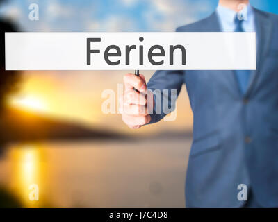 Ferien (Urlaub in deutscher Sprache) - Geschäftsmann Hand mit Schild. Wirtschaft, Technologie, Internet-Konzept. Stock Foto Stockfoto