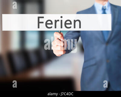 Ferien (Urlaub in deutscher Sprache) - Geschäftsmann Hand mit Schild. Wirtschaft, Technologie, Internet-Konzept. Stock Foto Stockfoto