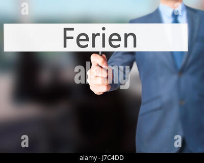 Ferien (Urlaub in deutscher Sprache) - Geschäftsmann Hand mit Schild. Wirtschaft, Technologie, Internet-Konzept. Stock Foto Stockfoto