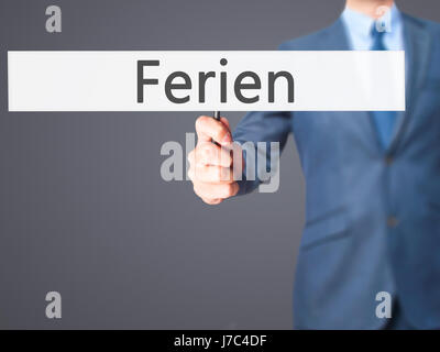 Ferien (Urlaub in deutscher Sprache) - Geschäftsmann Hand mit Schild. Wirtschaft, Technologie, Internet-Konzept. Stock Foto Stockfoto