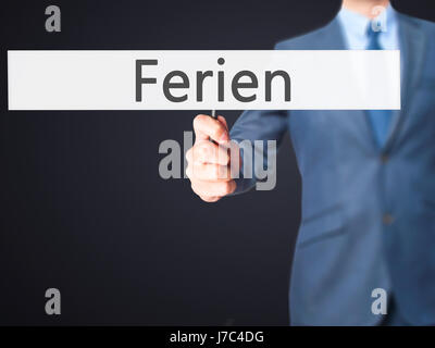 Ferien (Urlaub in deutscher Sprache) - Geschäftsmann Hand mit Schild. Wirtschaft, Technologie, Internet-Konzept. Stock Foto Stockfoto