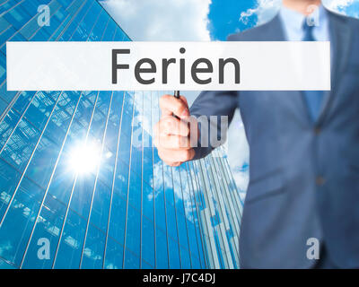 Ferien (Urlaub in deutscher Sprache) - Geschäftsmann Hand mit Schild. Wirtschaft, Technologie, Internet-Konzept. Stock Foto Stockfoto