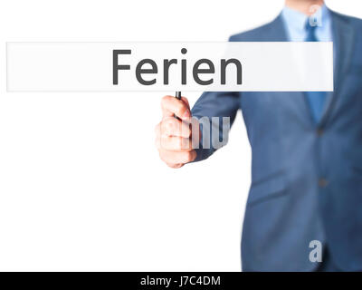 Ferien (Urlaub in deutscher Sprache) - Geschäftsmann Hand mit Schild. Wirtschaft, Technologie, Internet-Konzept. Stock Foto Stockfoto