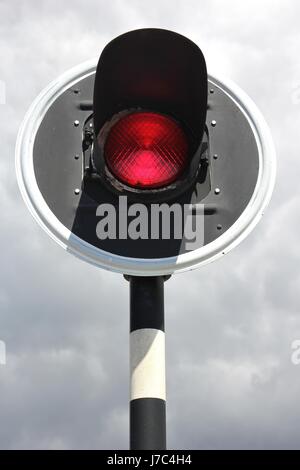 rote Ampel gegen bewölktem Himmel Stockfoto