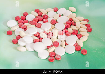 Rot, weiß und gelb Drogen, Pillen, Pulver, Haufen, medizinische, homöopathische, grüner Hintergrund, Nahaufnahme. Stockfoto