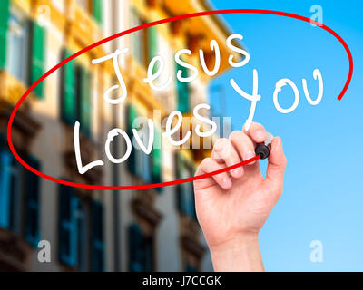 Hand des Menschen Jesus Loves You mit schwarzem Filzstift auf Bildschirm zu schreiben. Isoliert auf Stadt. Religion, Technik, Internet-Konzept. Stock Bild Stockfoto