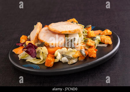 Caesar Salat mit Sonnenblumenkernen auf dunklen schwarzen Hintergrund. Kulinarischen Salat essen. Stockfoto