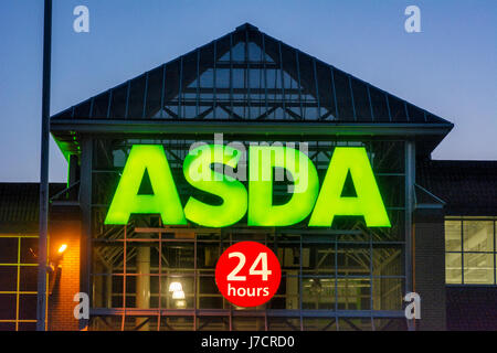 ASDA 24 Stunden Supermarkt Zeichen gegen den Abendhimmel bei Sonnenuntergang beleuchtet. Stockfoto