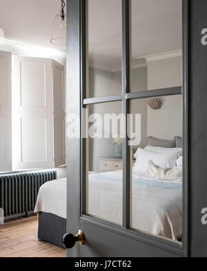 Blick durch die verglasten Tür in elegante Schlafzimmer mit Fenster Fensterläden und Bügeleisen Kühler Stockfoto