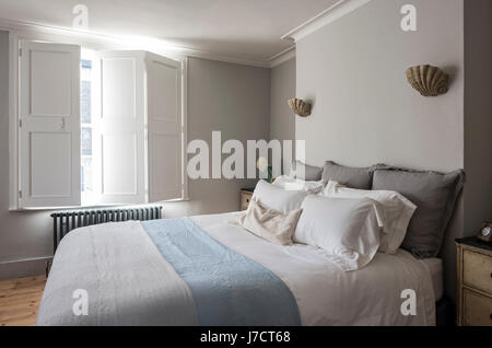 Elegante Schlafzimmer mit Fenster Fensterläden und Jakobsmuschel Wandleuchte Beleuchtung von Cox london Beleuchtung. Stockfoto