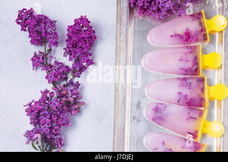 Eis am Stiel mit lila Blumen Stockfoto