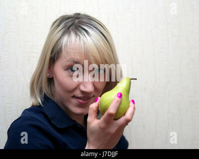 Schöne blonde Frau zu essen eine frische Birne, Studio-Porträt Stockfoto