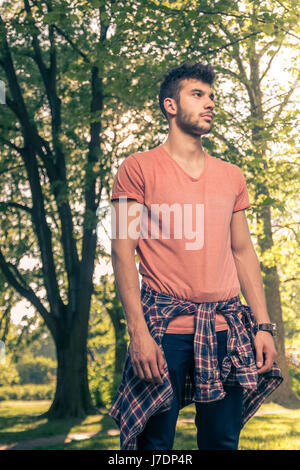 ein junger Erwachsener Mann nur, lässige Kleidung, seitwärts, Park-Natur Stockfoto