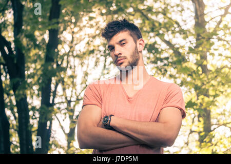 ein junger Mann, Arme gekreuzt, Oberkörper, Blick auf die Kamera, im freien sonnigen Tag, Naturpark Stockfoto